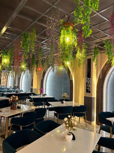 un restaurante con mesas, sillas y plantas en Royal Chandra Hotel en Patna