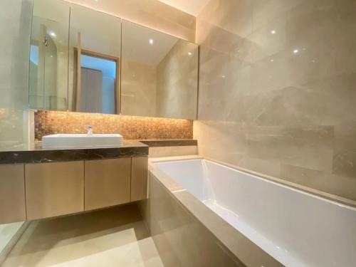 ein Badezimmer mit einer Badewanne, einem Waschbecken und einem Spiegel in der Unterkunft Chit Lom, Siam BTS, Perfect Best Location High Floor Sleeps 4 81sqm in Bangkok