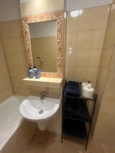 een badkamer met een wastafel, een bad en een spiegel bij Apartament Mazurek przy Promenadzie in Mikołajki