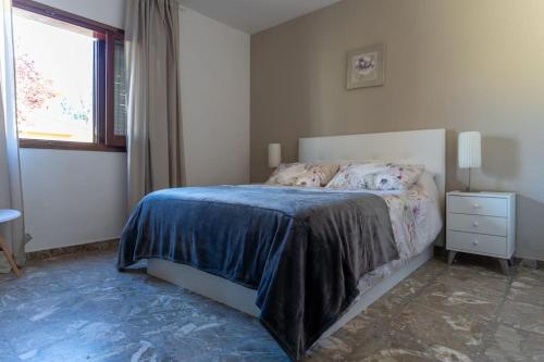 a bedroom with a bed with a blue blanket and a window at Villa particular, confortable. in Benicàssim