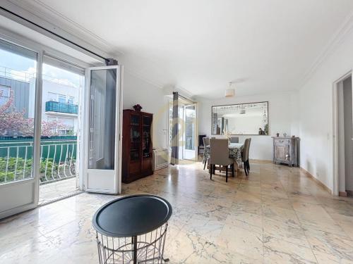 un salon avec une table, des chaises et des fenêtres dans l'établissement JO Family House, à Nanterre