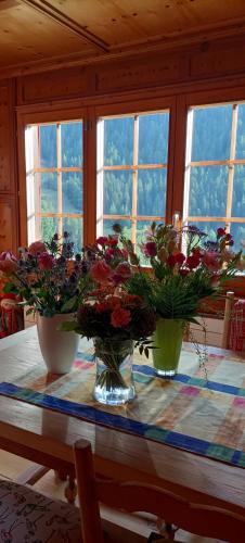 two vases of flowers on a table in a room at The Raven B&B in Ayer