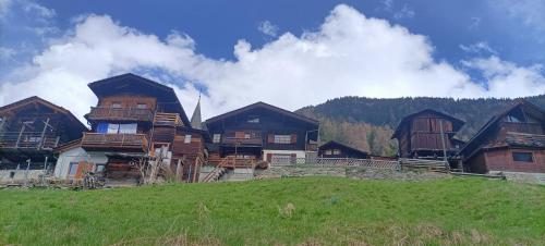 a group of wooden buildings on a hill with a field at The Raven B&B in Ayer