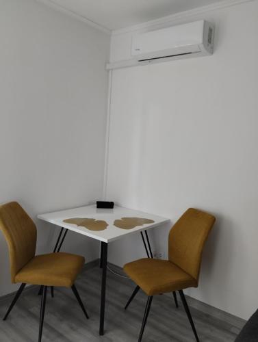 a white table with two chairs and a white wall at Love Lair Apartman in Miskolc