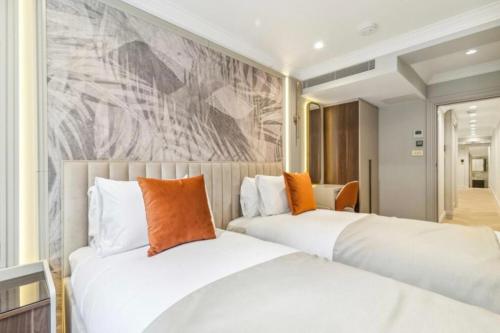 ロンドンにあるLuxury 2 bed Apartmentの壁に絵画が飾られたホテルルーム内のベッド2台