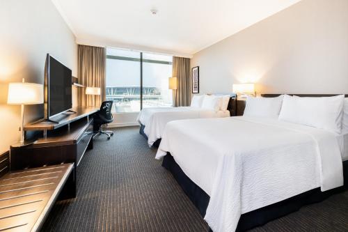 a hotel room with two beds and a flat screen tv at Holiday Inn Santiago - Airport Terminal, an IHG Hotel in Santiago