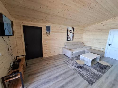 een woonkamer met een witte bank in een houten kamer bij Kucica Una in Ulcinj