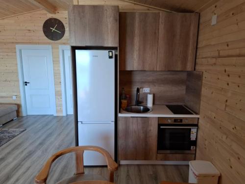 a kitchen with a refrigerator and a clock on the wall at Ada Bojana kucica Una in Ulcinj