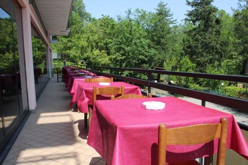 a row of tables with pink table cloths on a balcony at Hotel Nord Ovest in Monte Grimano Terme