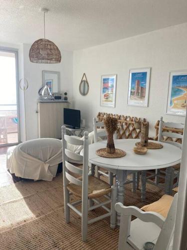 une salle à manger avec une table et des chaises blanches dans l'établissement Magnifique appartement face mer, à Canet