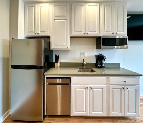 a kitchen with white cabinets and a stainless steel refrigerator at The GEM Museum Suites in Evanston