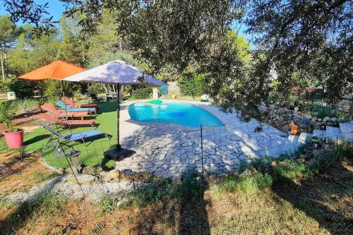 - une vue sur la piscine avec un parasol dans l'établissement Près des Arcs sur Argens belle villa avec piscine sur un demi hectare, à Draguignan