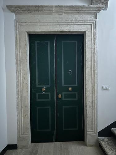una porta verde con una cornice di pietra in una stanza di Case Pacifici in città ad Ascoli Piceno