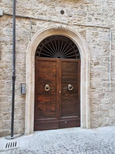 a large wooden door in a stone building at Case Pacifici in città in Ascoli Piceno