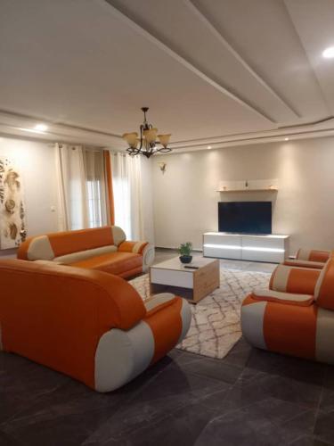 ein Wohnzimmer mit orangefarbenen Möbeln und einem Flachbild-TV in der Unterkunft Appartement à Entrée Personnelle Abomey-Calavi ZOPAH in Abomey-Calavi