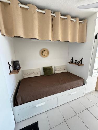 Bett in einem Zimmer mit Vorhängen darauf in der Unterkunft STUDIO BELLE PLAGE in Leucate