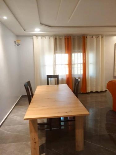 einen Holztisch und Stühle in einem Zimmer in der Unterkunft Appartement à Entrée Personnelle Abomey-Calavi ZOPAH in Abomey-Calavi