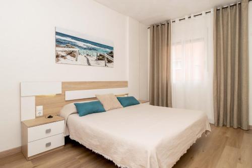 a white bedroom with a bed and a window at Jose Hurtado Apartamento in Torrevieja