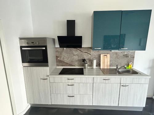 a white kitchen with a sink and a microwave at Modern eingerichtetes Apartment zum entspannen und wohlfühlen in Oldenburg