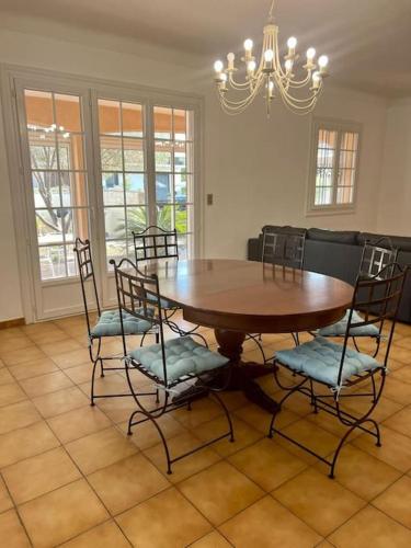 une salle à manger avec une table et des chaises en bois dans l'établissement Maison avec piscine à 3min à pied de la mer, à Canet