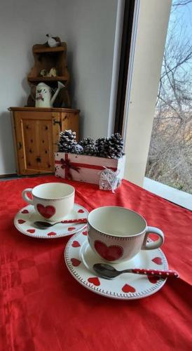 two cups and saucers sitting on a red table at Casa rustica con vista meravigliosa in Offida