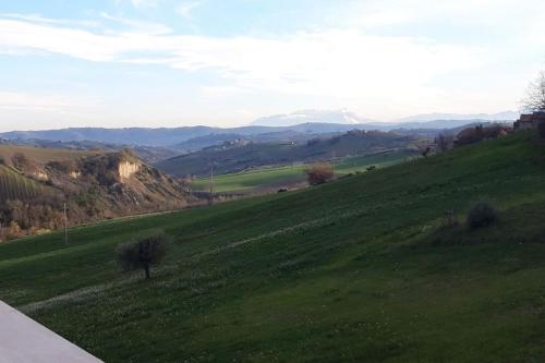a green field with mountains in the background at Casa rustica con vista meravigliosa in Offida