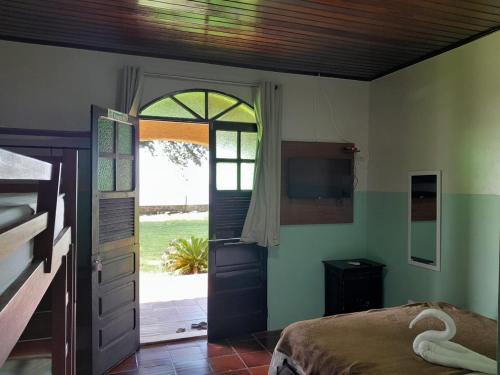 sypialnia z drzwiami, łóżkiem i telewizorem w obiekcie Hotel e Pousada Marajó w mieście Salvaterra