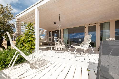 - une terrasse couverte avec des chaises blanches et une balançoire dans l'établissement Buqez 58 - Drage villas, à Drage