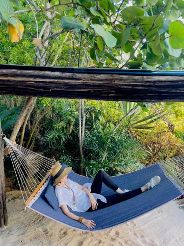 a woman laying in a hammock on the beach at Casa El Paraiso, Eco Lodge in Santa Bárbara de Samaná