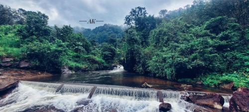 a plane flying over a river with a waterfall at The Serene Cottage in Viripara