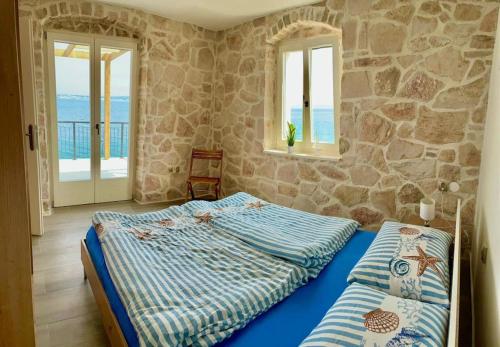 a bedroom with a bed and a stone wall at Villa Ocean View of Kali - Erste Meerreihe mit Pool in Kali