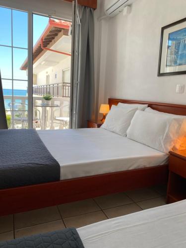 a bedroom with a bed and a view of the ocean at Korali Hotel in Paralia Katerinis