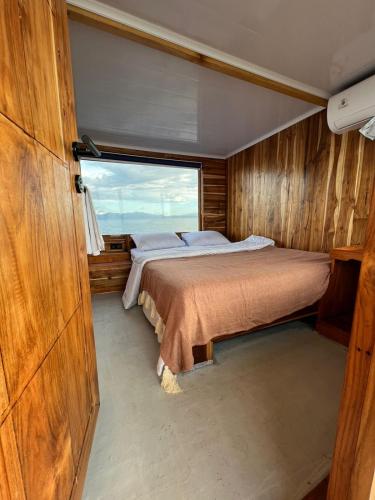 a bedroom in a boat with a large window at Jelajah komodo in Labuan Bajo