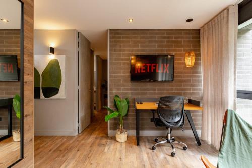 an office with a desk and a tv on a brick wall at Loma Verde Aparthotel in Medellín