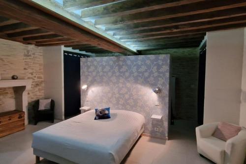ein Schlafzimmer mit einem weißen Bett und einem Stuhl in der Unterkunft Charmante maison au coeur du Limousin - Comme à la maison in Lussac-les-Églises