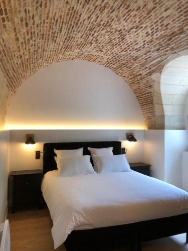 una camera da letto con un grande letto e un soffitto in mattoni di la maison du philosophe a Amboise