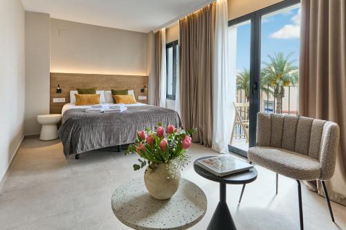 Un dormitorio con una cama y una mesa con un jarrón de flores en El Pont Alicante Apartments, en Alicante