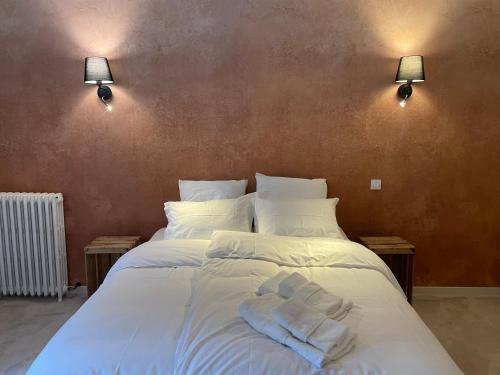 1 cama con sábanas blancas y 2 luces en la pared en La Maison Voyage Bed and Breakfast, en Onzain