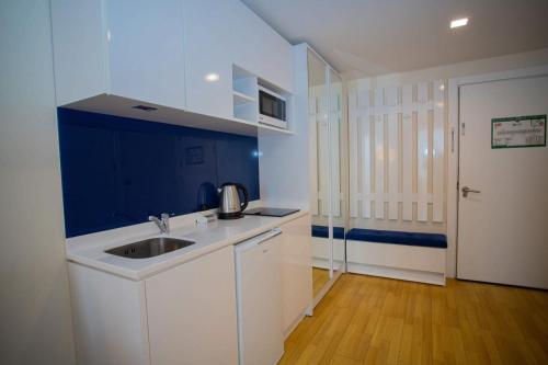 a white kitchen with a sink and a blue wall at Suites in Orbi City Batumi in Batumi
