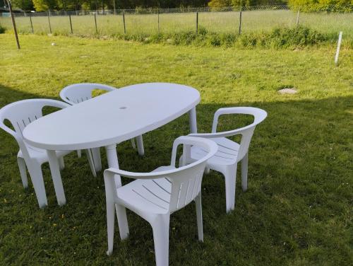 une table blanche et quatre chaises dans l'herbe dans l'établissement location pour 24h du mans, à Arnage