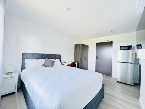 a bedroom with a large white bed and a refrigerator at Main Residences in Beenleigh