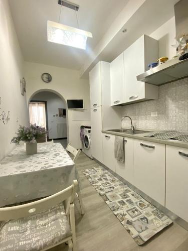 a kitchen with white cabinets and a table with chairs at Casa Sole E Luna in Genova