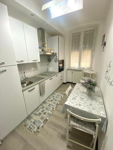 a white kitchen with a table and a sink at Casa Sole E Luna in Genova