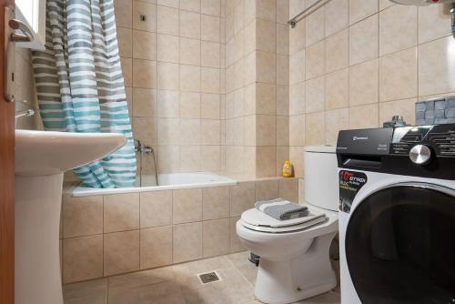uma casa de banho com um WC, um lavatório e uma máquina de lavar roupa em Cleri's Apartment em Nea Peramos