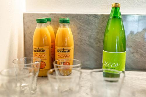 four bottles of orange juice and glasses on a table at Villa Fedora Luxury Suites in Lucca