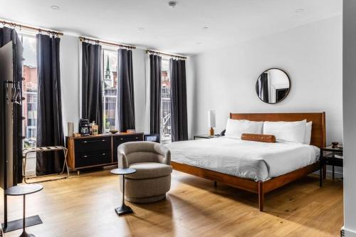 a bedroom with a bed and a chair and windows at Historic Hotel, King Bed, Market Square View, Room # 201 in Bangor