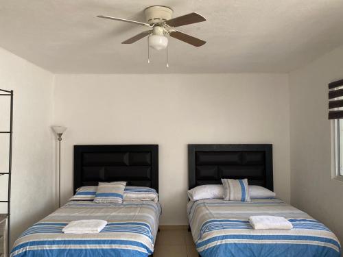 two beds in a room with a ceiling fan at Apartamentos Amplios Alfa # 238 in Monterrey