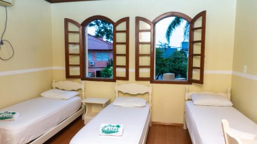 two beds in a room with two windows at Hotel Castel in Canoas