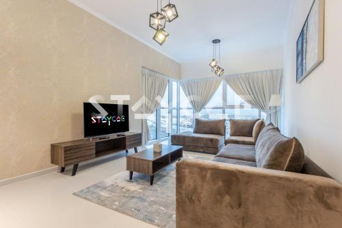 a living room with a couch and a tv at Staycae Holiday Homes - Carson Towers in Dubai