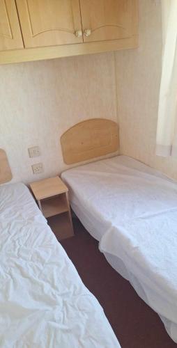 een kamer met 2 bedden en een kleine tafel bij Julie's caravans in Lincolnshire